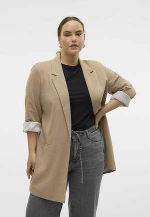Bežs žakets ar sarullētām piedurknēm, kombinēts ar melnu kreklu un pelēkiem augsto vidukli džinsiem. Gluda auduma, ar vienu kabatu uz žaketa.