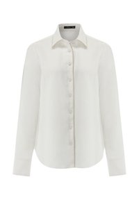 Camicia bianca a maniche lunghe con colletto appuntito, bottoni frontali e dettagli di cucitura discreti lungo la patta e i polsini. Texture morbida.