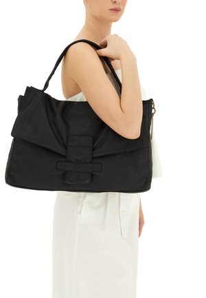 Borsa a mano in pelle nera con una grande patta, dotata di un accento centrale a forma di fiocco e una cerniera dorata su un lato. Texture liscia e forma strutturata.