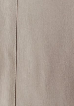 Bežs teksturēts audums ar diagonālu austumu rakstu un vertikālu šuvi gar malu. Materiāls izskatās mīksts un diskrēts.