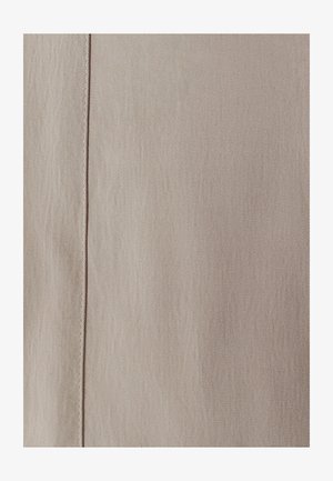 Beige strukturierter Stoff mit einem diagonalen Gewebemuster und einer Naht, die vertikal entlang der Kante verläuft. Das Material wirkt weich und subtil.