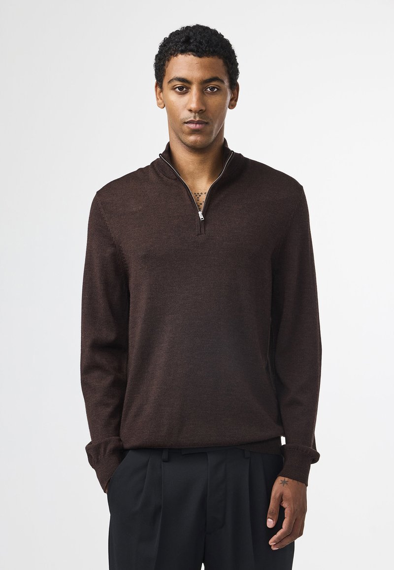 Brauner Pullover mit Halb-Reißverschluss-Kragen, aus weichem Stoff, mit langen Ärmeln und figurbetontem Schnitt. Keine auffälligen Muster oder Akzente.