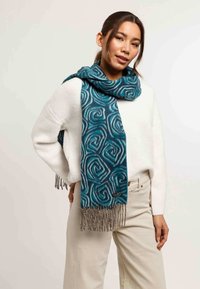Sciarpa teal con un motivo vorticoso e accenti bianchi, realizzata in materiale morbido e rifinita con frange grigie chiare.