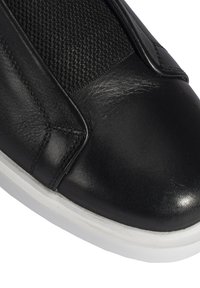 Zwarte leren sneaker met een gestructureerde zwarte bovenkant, een ronde neus en een witte rubberen zool. Bevat minimale stiksels en elegante ontwerpkenmerken.