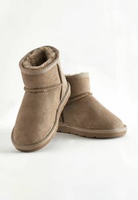 Bottines en suède tan avec une doublure en fourrure douce, bout rond et semelle en caoutchouc. Présente des accents cousus et un design simple et minimaliste.