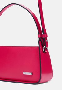 Borsa a tracolla rossa in pelle con una forma rettangolare elegante, rifiniture nere in contrasto, una tracolla corta e una placca con logo argentato sul lato.