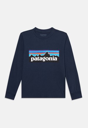 Tamnoplava košulja dugih rukava s logotipom Patagonije koji prikazuje siluete planina i šarene vodoravne pruge na prsima.