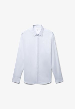 Chemise blanche à manches longues avec un plastron vertical fin, col classique et poignets à boutons. Tissu lisse et léger.