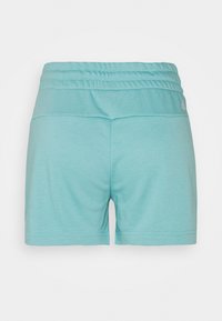Shorts à taille élastique bleu clair, design uni, vus de dos, avec un petit logo blanc sur la partie supérieure droite de la taille.