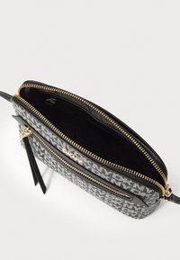 Borsa a mano con motivo bianco e nero, texture liscia, cerniere dorate e tasca interna. Include una tracolla nera rimovibile.