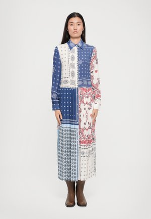 Robe maxi en patchwork avec des motifs bleus, blancs et rouges, dotée d'un col, de manches longues et d'un mélange de motifs floraux et géométriques. À assortir avec des bottes marron.