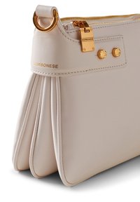 Light beige leather handbag featuring pleated design, gold hardware, and embossed logo. Zipper closure at the top. Smooth texture.