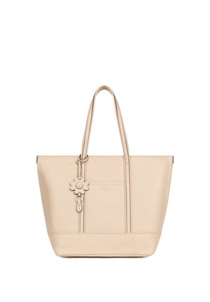 Sac fourre-tout en cuir beige avec doubles anses, poche avant et breloque fleur décorative suspendue à une anse.