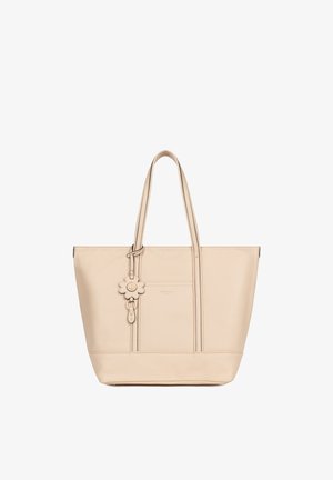 Sac fourre-tout en cuir beige avec doubles anses, poche avant et breloque fleur décorative suspendue à une anse.