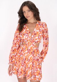 Mini-jurk met bloemenpatroon en lange mouwen. Heeft een diepe V-hals, een uitgesneden taille en een gekruide zoom in oranje, roze en witte kleuren.