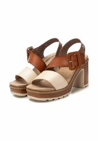 Sandalias de tacón beige y marrón con correas anchas, hebilla ajustable, plantilla texturizada y suela de plataforma con borde acanalado.