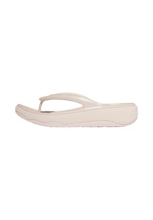 Beige gevoerde teenslipper met een dikke zool en gebogen teenriem, ontworpen voor casual gebruik en comfort.