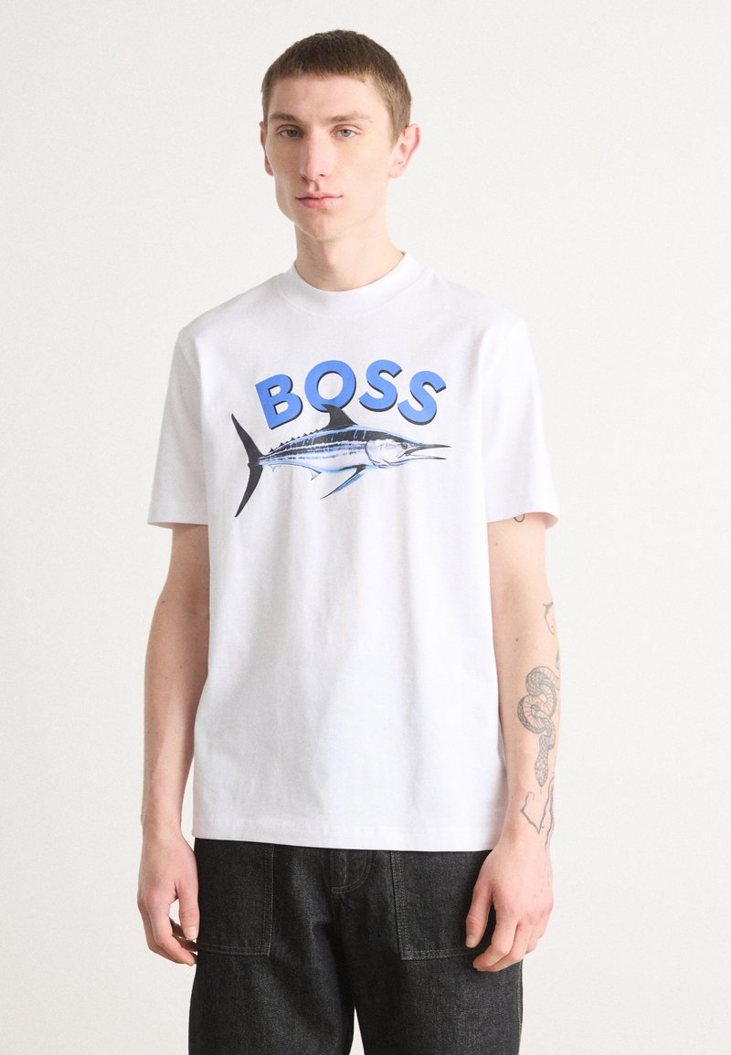Camiseta de algodón blanca con el texto azul "BOSS" y un gráfico de un pez marlín. Diseño de mangas cortas y cuello redondo. Corte casual.