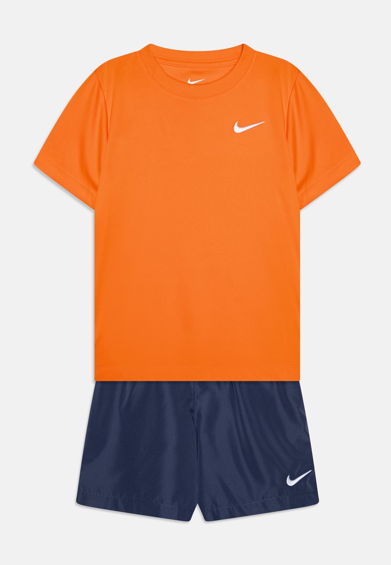 Conjunto atlético da Nike com uma t-shirt laranja de mangas curtas e calções azuis-marinho. A t-shirt tem um logo branco; os calções são lisos e leves.