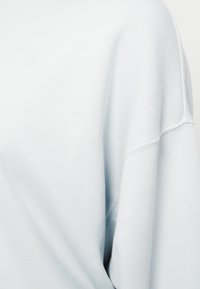 Γαλάζιο φούτερ με άνετη εφαρμογή, ριμπ λαιμόκοψη και διακριτική λεπτομέρεια με λογότυπο, κατασκευασμένο από μαλακό, υφασμάτινο ύφασμα με υφή.