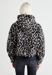 Skraćena flis dukserica s leopard printom u crnoj i ružičastoj boji, koja ima kapuljaču s uvećanom vrpcom i mekano, teksturirano platno. Crni detalji na rubu.