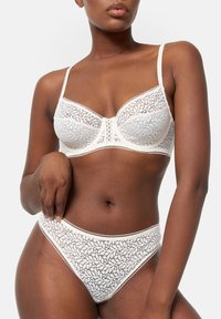 Ensemble de soutien-gorge et culotte en dentelle ivoire, présentant des motifs floraux, un soutien-gorge à armatures et des bretelles délicates. Tissu lisse avec des détails raffinés.