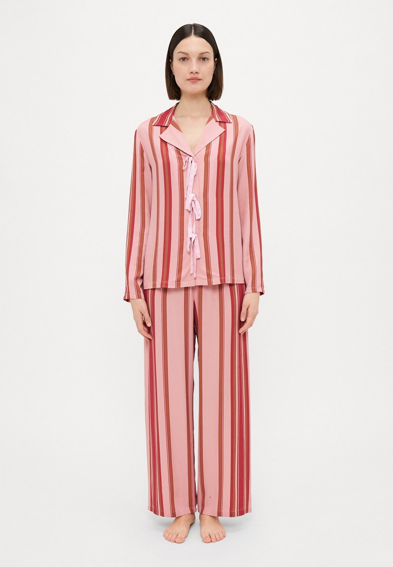 Roze en rode gestreepte pyjama set met een knoopsluiting bovenkant met kraag en strikdetail aan de voorkant, gecombineerd met wijde broekspijpen.