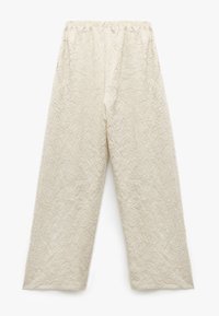 Beige strukturierte weite Hosen mit einer zerknitterten Optik und elastischem Bund. Der Stoff weist subtile vertikale Linien für zusätzliche Details auf.