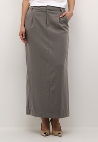 Gray maxi skirt made of smooth fabric, with front pleats and a tailored waist. Paired with beige heels featuring metallic accents.