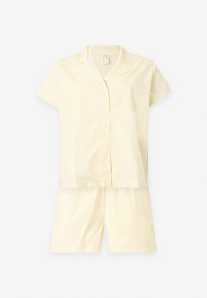 Haut de pyjama crème à manches courtes et boutonné, assorti à un short crème assorti sur fond blanc.