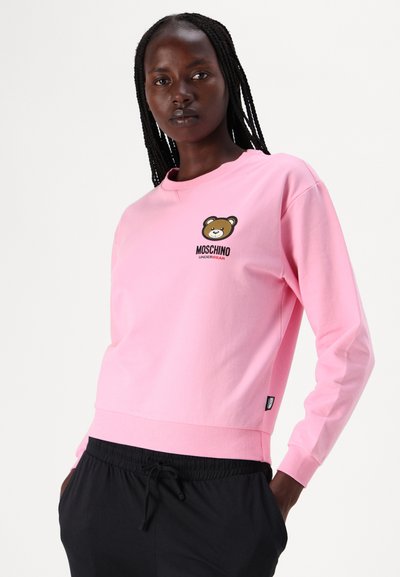 Ružový bavlnený sveter s dlhými rukávmi, ryhovanými manžetami a lemom. Na hrudi sa nachádza logo medveďa a text "Moschino Underbear".