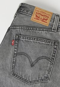 Πίσω τσέπη γκρι τζιν από denim με την κόκκινη ετικέτα της Levi's και δερμάτινη ετικέτα της μάρκας Levi Strauss & Co. ορατή στη μέση.