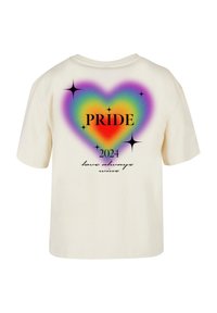 Cremefarvet bomulds t-shirt med et flerfarvet hjertegrafik, teksten "PRIDE 2024" og "kærlighed vinder altid" i sort kursiv nederst.