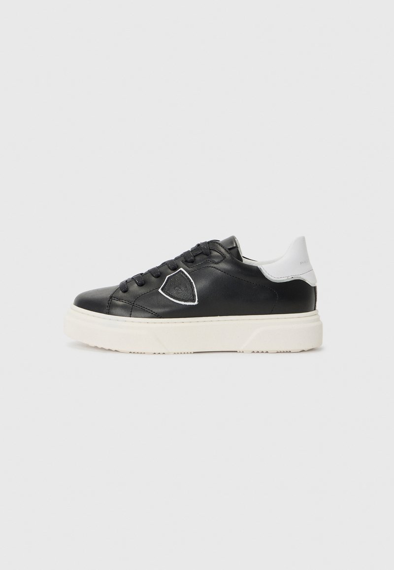 Baskets en cuir noir avec un accent blanc à l'arrière, bout rond, semelle épaisse blanche et couture décorative. Dotées de lacets noirs et d'un détail de logo.