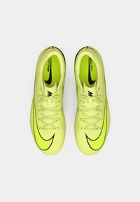 Las zapatillas de fútbol Nike Mercurial en un vivo color amarillo cuentan con un diseño elegante, una parte superior texturizada y acentos en negro, incluidos el swoosh y los cordones.