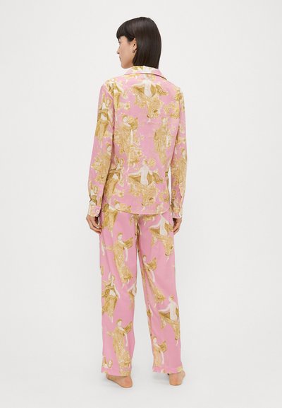 Conjunto de pijama rosa com uma estampa detalhada de anjos em dourado e branco. A parte de cima tem colarinho e mangas longas; as calças são largas.