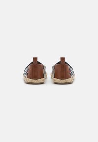 Espadrilles featuring a striped textile upper in blue and white, brown leather accents, and a natural jute sole with a textured finish.
