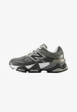Grijze en zwarte sportsneaker met witte veters, ademend mesh en dikke zool met het New Balance-logo aan de zijkant.