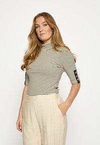 Pruhovaný rolák v bielej a čiernej farbe s polovičnými rukávmi; má čierne akcenty a gombíkové detaily na rukávoch.