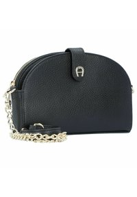 Bolso de mano de cuero negro con un diseño redondeado, acabado texturizado, herrajes dorados, cierre de cremallera y correa de cadena desmontable.