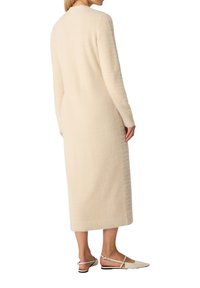 Abito lungo di colore crema in maglia, con maniche lunghe e taglio dritto. Tessuto morbido con una finitura leggermente pelosa. Lunghezza fino al polpaccio.