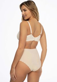 Beżowy koronkowy braletka z regulowanymi ramiączkami i skropionymi detalami, w połączeniu z gładkimi, beżowymi majtkami o wysokim stanie; obie części podkreślają bezszwowy design.