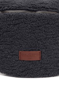 Borsa rotonda in morbido tessuto grigio scuro con cerniera argentata e una targhetta in pelle marrone con la scritta "nice things bags". Aspetto testurizzato e soffice.