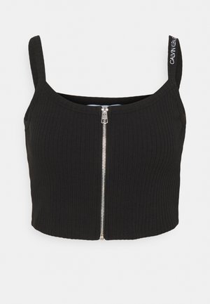 Black ribbed crop top with front silver zipper and branded strap on right shoulder reading "Calvin Klein Jeans."