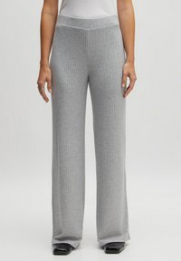 Gray ribbed wide-leg pants with a textured fabric, elastic waist, and contrasting black footwear. The design features vertical ribbing throughout.