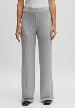 Grijze geribde wijde broek van een gestructureerde stof, met een elastische taille en contrasterend zwart schoeisel. Het ontwerp heeft verticale ribbels in de gehele broek.