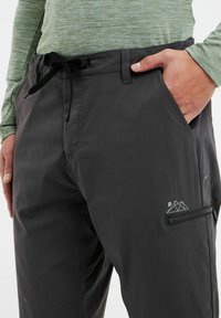 Zwarte, lichte, sneldrogende cargobroek met verstelbare taille, zijzakken en een ritssluitingzak. Kenmerkt een mountainlogo-detail.