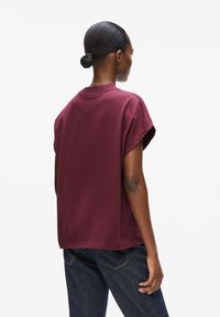 Burgunderfarbenes Kurzarm-T-Shirt mit lockerer Passform, rundem Halsauschnitt und weichem Baumwollmaterial. Einfaches, minimalistisches Design.