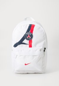 Mochila blanca con el logo del Paris Saint-Germain, con franjas rojas y marinas. Incluye un bolsillo frontal y un detalle del swoosh rojo de Nike.