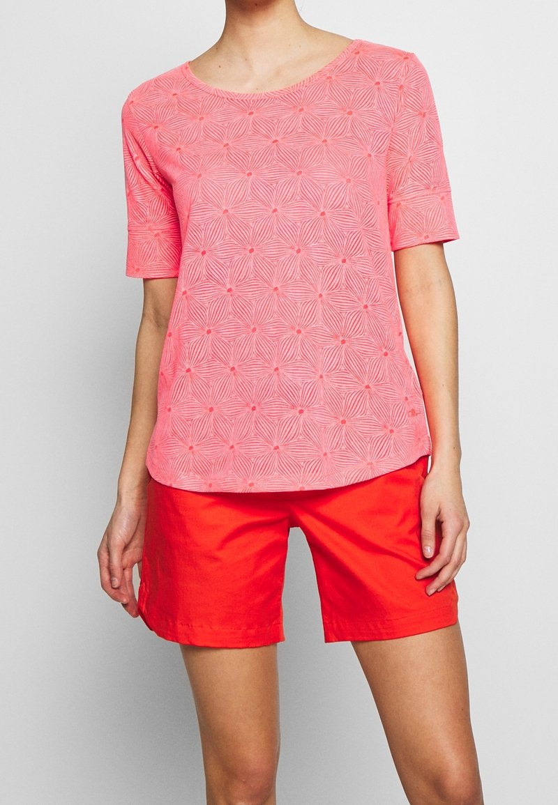 Top de un brillante color rosa con un patrón de burbujas texturizadas, cuello redondo y mangas cortas, combinado con pantalones cortos rojos de corte recto.